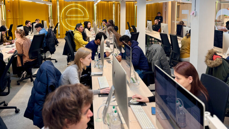 Students at Hive Helsinki coding together in a modern open workspace filled with computers