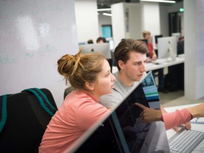 Students at Hive Helsinki collaborating on a coding project together in a modern computer lab.