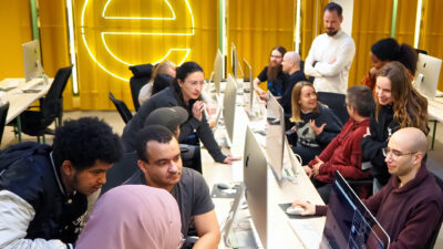 Hive Helsinki students collaborating in a computer lab, coding together and sharing ideas.